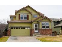 Charming two-story home featuring an attached garage, lush green lawn, and appealing architectural details at 16738 E 106Th Pl, Commerce City, CO 80022
