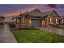 Charming single-Gathering home showcasing a stone exterior, attached garage, and well-maintained lawn at dusk at 24943 E Phillips Pl, Aurora, CO 80016