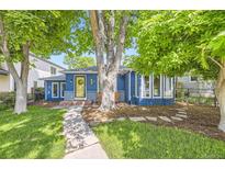 Charming blue home featuring a well-maintained lawn, mature trees, and a welcoming yellow front door at 2684 S Adams St, Denver, CO 80210