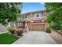 Charming two-story home with brick and siding, complemented by a well-manicured lawn and mature trees at 14682 W Amherst Pl, Lakewood, CO 80228