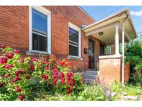 Charming brick home featuring a cozy covered porch and vibrant landscaping, including colorful roses at 22 E Bayaud Ave, Denver, CO 80209