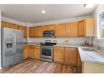 Well-lit kitchen features stainless steel appliances, light wood cabinets and marbled countertops at 1842 Reliance Cir, Superior, CO 80027