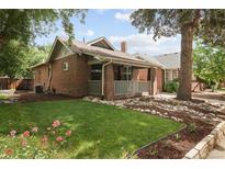 Charming brick home with a welcoming front porch, grassy lawn, and beautiful landscaping at 3039 W Denver Pl, Denver, CO 80211