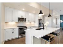 Modern kitchen with white cabinets, stainless steel appliances, and a center island at 1565 W 67Th Ave, Denver, CO 80221