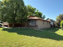 Charming single-story home with lush front lawn and mature shade tree on a sunny day at 8995 E Cornell Ave, Denver, CO 80231
