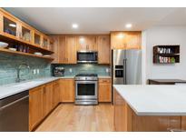 Well-lit kitchen with light wood cabinets, stainless steel appliances, and an island with a white countertop at 3701 Arapahoe Ave # 304, Boulder, CO 80303