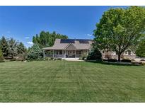 Inviting home featuring a spacious lawn, charming porch, and solar panels on the roof at 6633 E 166Th Pl, Brighton, CO 80602