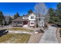 Charming two-story home with brick accents, a covered porch, manicured lawn, and a vibrant red front door at 8389 Owl Roost Ct, Parker, CO 80134