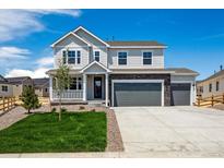 Two-story home with light gray siding, stone accents, a three-car garage, a manicured lawn and a charming front porch at 39141 Anthony St, Elizabeth, CO 80107