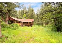 Charming cabin nestled among tall pines with a cozy front porch and lush, green surroundings at 35106 Boulder Canyon Dr, Boulder, CO 80302
