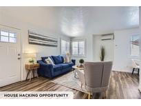 Cozy living room featuring a plush blue sofa, hardwood floors, and an abundance of natural light at 2060 W Iliff Ave, Englewood, CO 80110