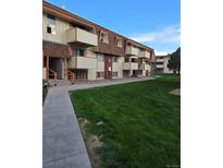 Inviting condo exterior featuring lush green lawn, balconies, and well-maintained common areas at 10211 Ura Ln # 9-308, Thornton, CO 80260