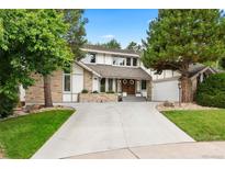 Charming home with a stone and stucco facade, mature trees, and a spacious driveway leading to an attached garage at 7703 S Grape Ct, Centennial, CO 80122