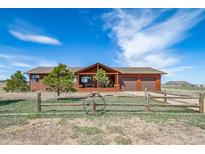 Charming ranch-style home featuring a rustic wood exterior, covered porch, and a two-car attached garage at 12973 Mesa View Rd, Larkspur, CO 80118
