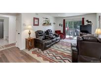 Comfortable living room featuring a leather reclining sofa set and outdoor access at 3550 S Harlan St # 249, Denver, CO 80235