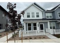Charming gray townhome featuring a white fence, a well-maintained yard, and a welcoming entrance at 14556 W 91St Ave # D, Arvada, CO 80005