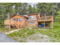 Charming log cabin with spacious deck surrounded by lush greenery and a beautifully landscaped yard at 8758 S Murphy Gulch Rd, Littleton, CO 80127