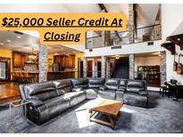 Spacious living room with stone columns, an open staircase, a large leather couch, and lots of natural light at 12570 W 60Th Ave, Arvada, CO 80004