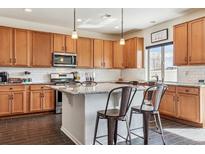 Spacious kitchen features stainless steel appliances, island with barstool seating, and tile backsplash at 5352 Truckee St, Denver, CO 80249