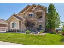 Charming two-story home featuring a stone facade, manicured lawn, and lush landscaping at 17102 W 85Th Pl, Arvada, CO 80007