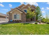 Charming two-story home with stone accents, lush green lawn, and professionally landscaped front yard at 17102 W 85Th Pl, Arvada, CO 80007