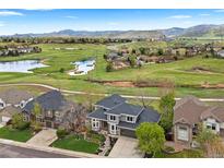Expansive aerial view showcases a stunning home, lush golf course, serene lake, and majestic mountain backdrop at 6656 S Oak Cir, Littleton, CO 80127