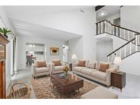 Bright living room features neutral decor, staircase, and opens to the kitchen for easy entertaining at 3274 S Heather Gardens Way, Aurora, CO 80014