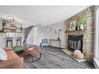 Cozy living room featuring a stone fireplace, hardwood floors, and modern decor at 9467 W Ontario Dr, Littleton, CO 80128