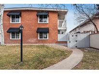 Charming brick building featuring black window awnings, a white gate, and a well-kept lawn at 160 Jackson St # 5, Denver, CO 80206