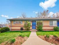 Charming single-story brick home with a well-manicured lawn and inviting blue entry door under a partly cloudy sky at 4201 Shoshone St, Denver, CO 80211