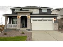 Charming two-story home with stone accents, covered porch, and a white garage door at 687 Raindance St, Erie, CO 80516