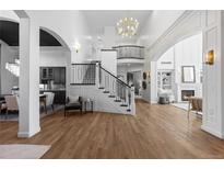 Bright and airy living room featuring grand staircase, chandelier, and open floor plan at 948 Buffalo Ridge Rd, Castle Pines, CO 80108