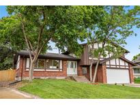 Charming two-story brick home with well-maintained lawn and mature trees on a sunny day at 13052 W Asbury Pl, Lakewood, CO 80228