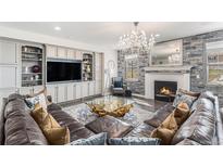 Inviting living room with a stone fireplace, elegant chandelier, and comfortable leather sectional sofa at 2627 Hillcroft Ln, Castle Rock, CO 80104