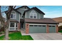 Attractive two-story home with a well-maintained lawn, brick accents, and a two-car garage at 10052 Sage Sparrow Ct, Highlands Ranch, CO 80129