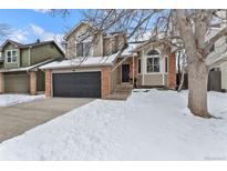 Two-story house with a brick facade and a black garage door, snow-covered yard at 96 S Lindsey St, Castle Rock, CO 80104