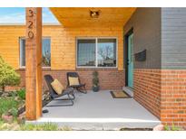 Inviting front porch with wood ceilings, chairs, potted plants and a painted brick accent wall at 1320 Locust St, Denver, CO 80220