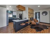 Open living room with hardwood floors, a modern fireplace, a kitchen view, and natural light at 1320 Locust St, Denver, CO 80220