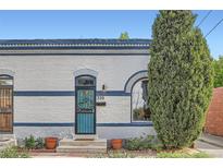 Charming home featuring a blue door, brick exterior, and a well-maintained front garden at 320 E Dakota Ave, Denver, CO 80209