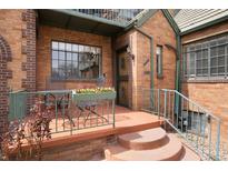 Charming brick home featuring an inviting front porch with wrought iron railings and seating area at 1419 Dexter St, Denver, CO 80220