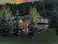 Two-story home with stone accents, arched windows and well-manicured lawn at dusk at 2191 Baldy Ln, Evergreen, CO 80439