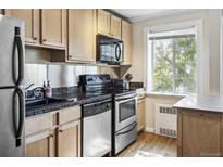 Well-lit kitchen features stainless steel appliances, black granite countertops, and hardwood floors at 1450 Albion St # 206, Denver, CO 80220