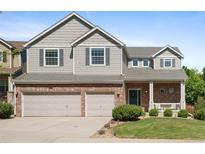 Charming two-story home featuring a brick facade, attached two-car garage, and well-manicured lawn at 10511 Jaguar Gln, Lone Tree, CO 80124