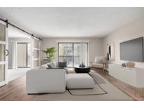 Bright living room features sliding barn doors, balcony access and light, neutral decor at 14050 E Linvale Pl # 309, Aurora, CO 80014