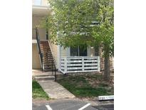 Charming condo exterior with white-fenced patio, complemented by lush trees and a stairway entrance at 8555 Fairmount Dr # A108, Denver, CO 80247
