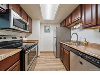 Well-lit kitchen features stainless steel appliances, wood cabinets and light countertops at 8555 Fairmount Dr # A108, Denver, CO 80247