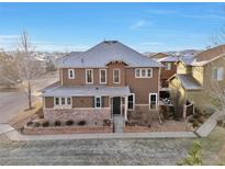 Two-story home with brown siding, gray roof and landscaping at 10555 Ashfield St, Highlands Ranch, CO 80126