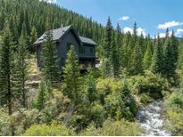 Secluded mountain home surrounded by a forest with a creek in the foreground at 379 Rainbow Rd, Idaho Springs, CO 80452