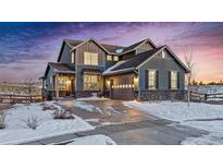Two-story house with gray siding, stone accents, and a three-car garage in a snowy landscape at 8086 S Grand Baker Way, Aurora, CO 80016
