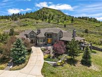 Stunning stone home with manicured landscaping and a circular driveway, set against a beautiful mountain backdrop at 4222 Serenade Rd, Castle Rock, CO 80104
